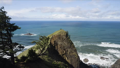 aerial panoramic view of coastal green hill overlooking turquoise ocean, god's thumb, oregon coast, wide shot