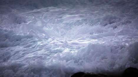 water level view of waves crashing and rolling into a rocky shore in slow motion 1