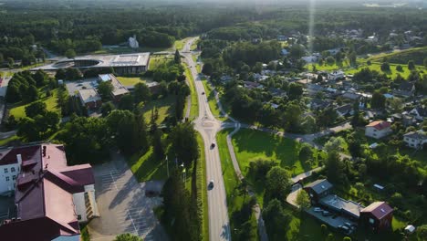 aerial drone hyperlapse of a small town or a city with traffic moving fast in front of a historic old white majestic library during summer sunset. chimney smoking in the horizon and forest is visible
