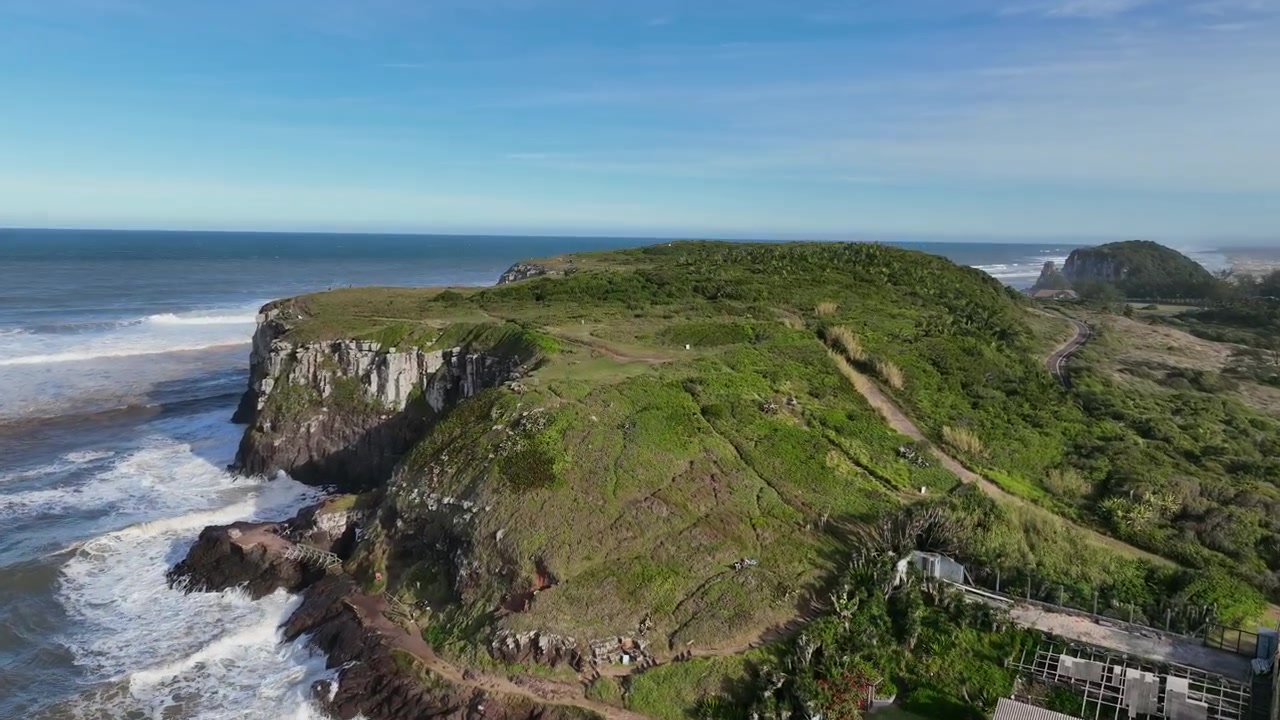 Scogliera di Morro da Guarita con vegetazione verde e onde oceaniche durante un'avanzata