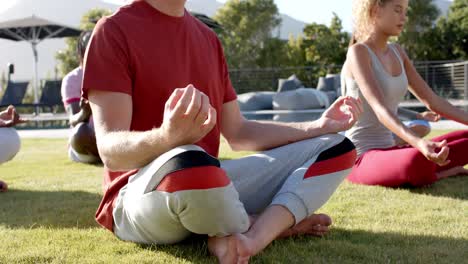 Amigos-Diversos-Enfocados-Practicando-Meditación-De-Yoga-Juntos-Sentados-En-Un-Jardín-Soleado,-Cámara-Lenta