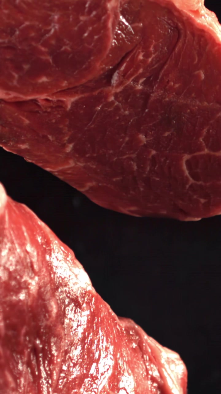 Raw Beef Steaks with Marbling on Black Background