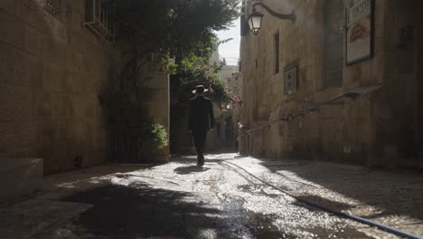 an orthodox jewish man walks through old streets of jerusalem