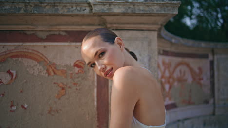 gorgeous tourist looking camera at antique wall place close up. portrait woman