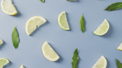 Video-of-slices-of-lemon-and-mint-leaves-lying-on-blue-background