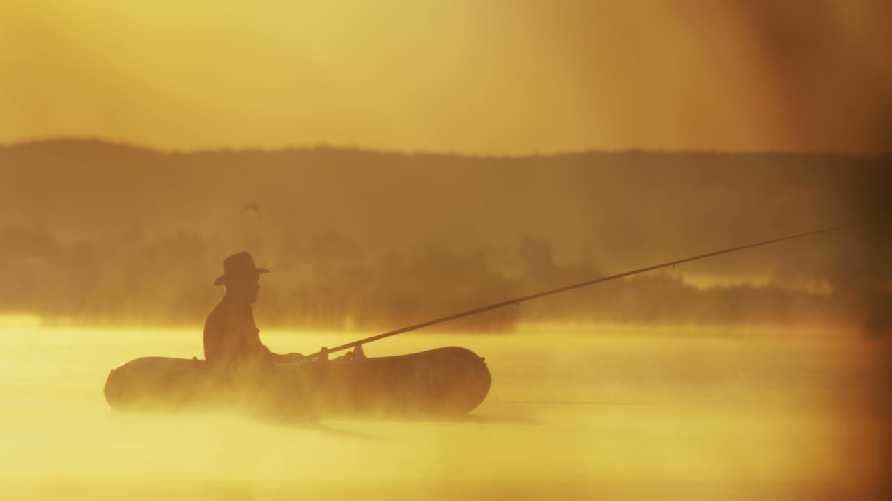 흐린 아침에 호수에서 막대로 낚시하는 보트에 모자를 쓴 노인의 먼 전망