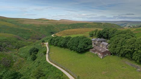 Imágenes-Aéreas-De-Drones-De-Los-Páramos-De-Los-Valles-Del-Campo-De-Yorkshire-Y-Moviéndose-Lentamente-Por-Un-Sendero-Hacia-Una-Granja-1