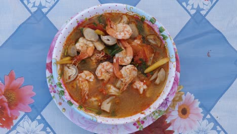 finished bowl of tom yam kung sitting on flowery table cloth