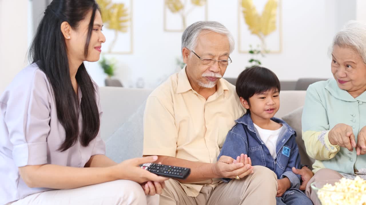 Multi-generational Asian family enjoying popcorn and conversation together in a cozy, joyful living room
