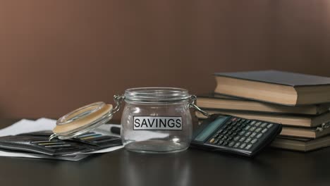 businessman puts money in glass with savings