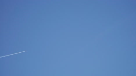 plane flying across the distant blue sky - across screen