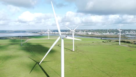 aerial view flying around renewable energy wind farm wind turbines spinning on british countryside orbiting left