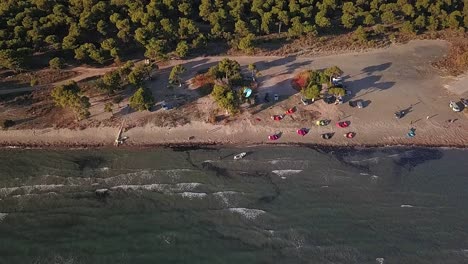 Neige-Dich-Nach-Oben,-Enthülle-Eine-Drohnenaufnahme-Eines-Strandes-In-Griechenland-Mit-Kitsurfern