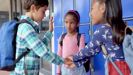 in school, group of children with backpacks putting hands together by lockers
