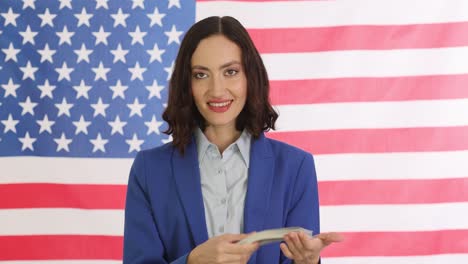 woman holding us dollars in front of american flag
