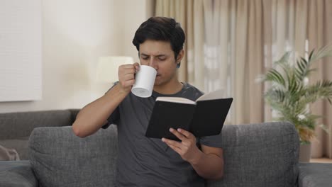 indian man reading a book and drinking coffee