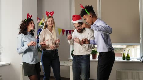 toma en cámara lenta: grupo de trabajadores de oficina felices bailando durante la fiesta corporativa de año nuevo usando sombreros navideños y diadema de ciervo