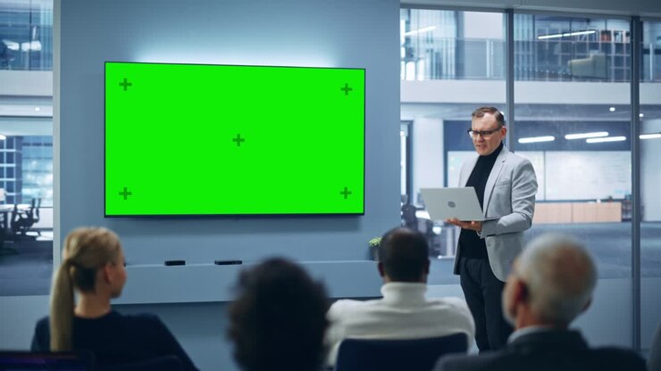 Evento di presentazione prodotto moderno: Uomo d'affari caucasico parla, usa una TV a parete con schermo chroma key verde. Conferenza stampa per un gruppo di investitori diversi, imprenditori digitali, uomini d'affari applaudono