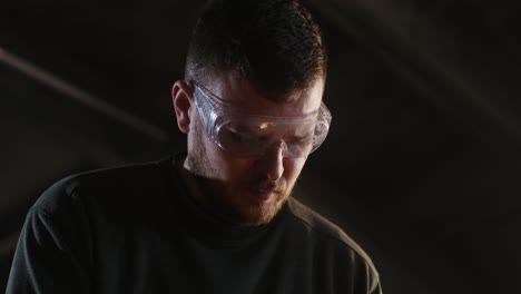 close-up of a man in safety glasses, focused on work