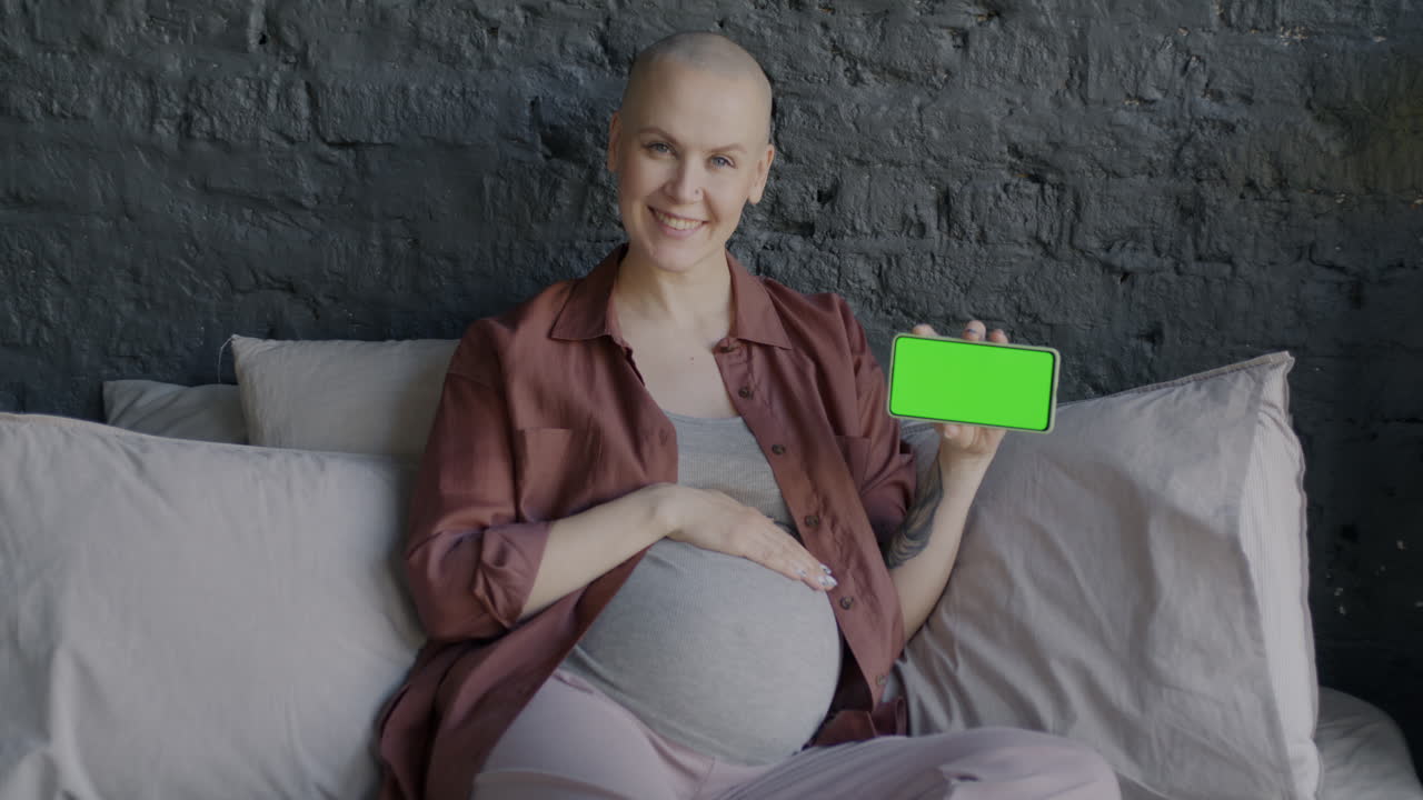 Mulher grávida segurando um smartphone com tela verde
