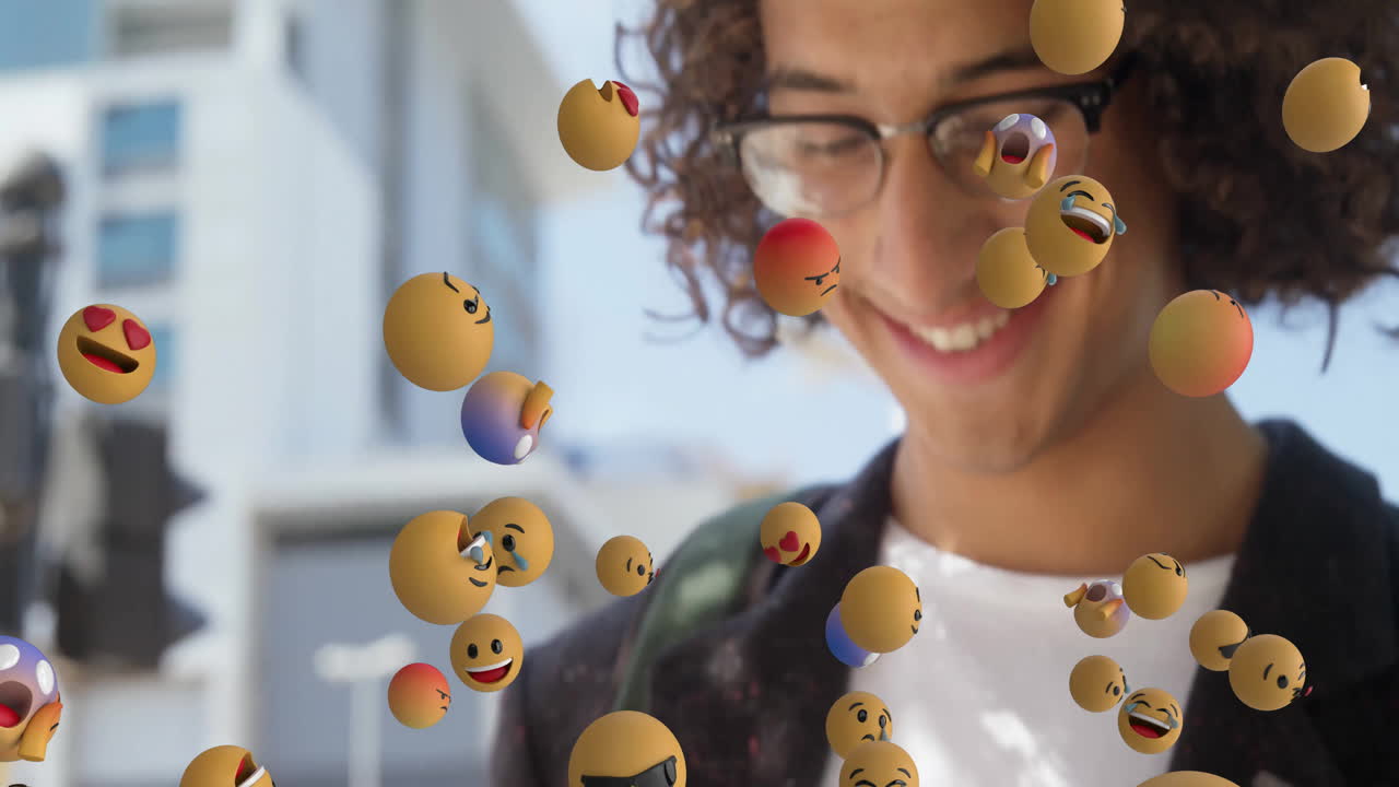 man wearing glasses smiling in outdoor plaza, featuring floating 3D emoji spheres for social media