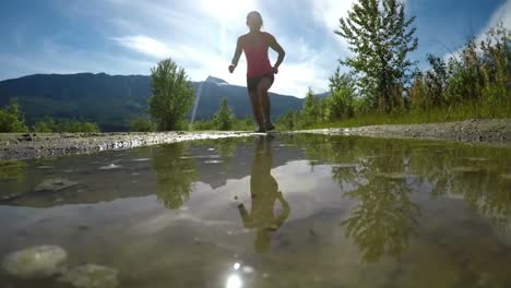 fit woman jogging through puddle 4k