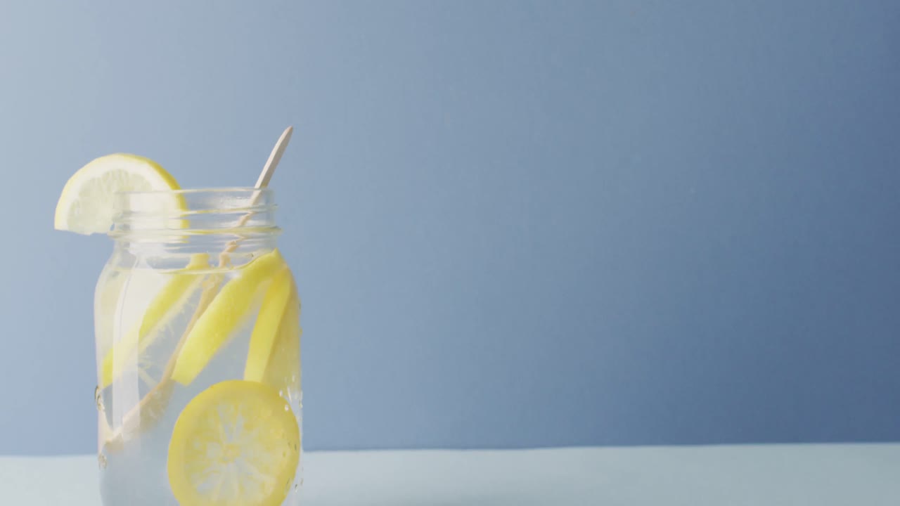 Video of jar with lemonade and straw on blue background