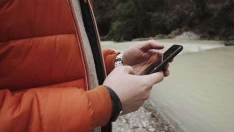 man using smartphone by a river