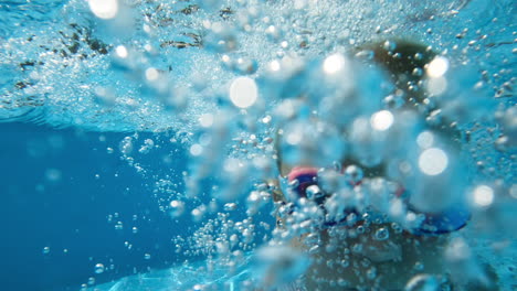 una joven nadando bajo el agua en una piscina