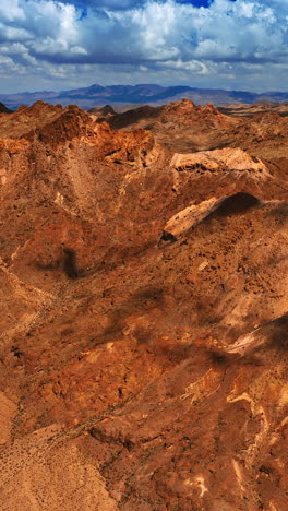 shadows from clouds moving by the bare rock tops. brown scenery of mountains in mojave desert under the cloudy sky. top view. vertical video