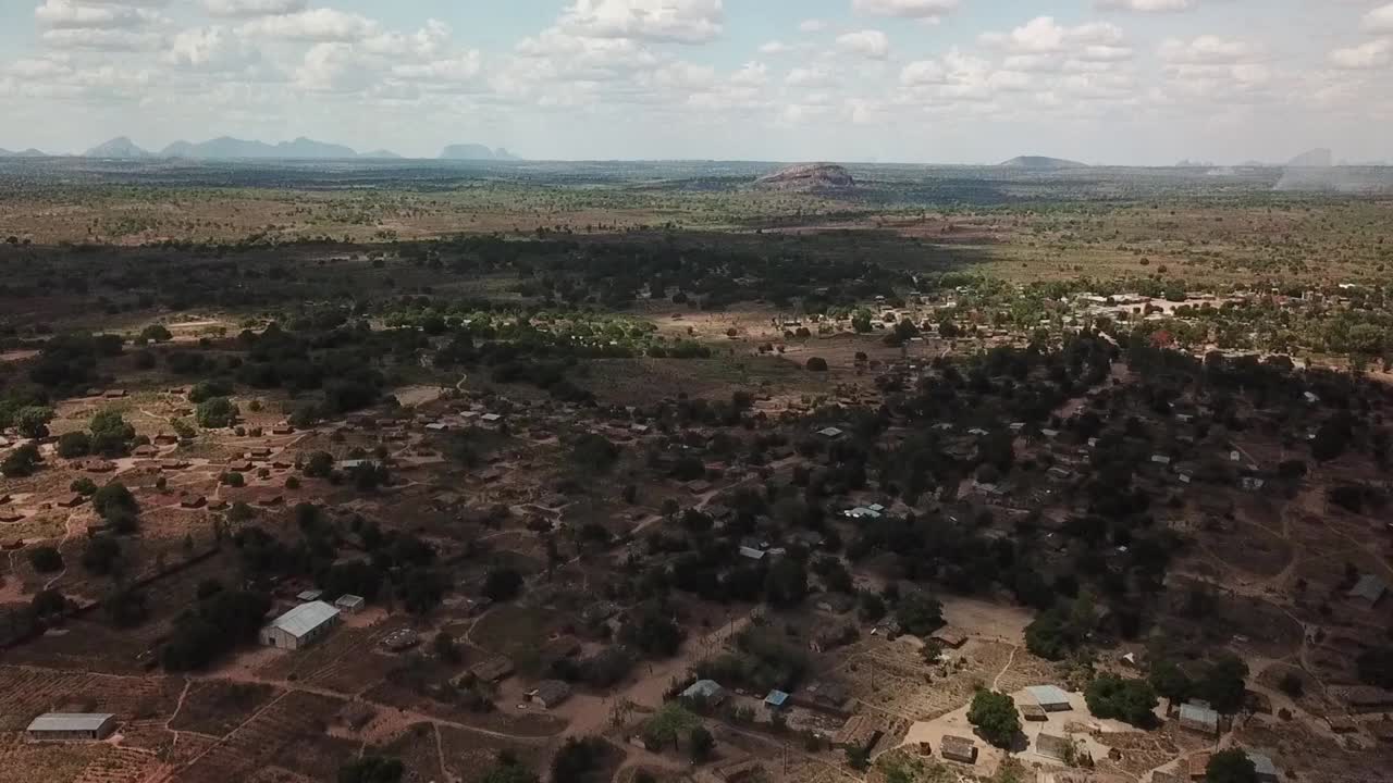 Aerial panorama of rural northern Mozambique (Nampula region), showing scattered villages and fields across dry savanna woodland, with isolated rocky hills (inselberg “island mountains”) on the