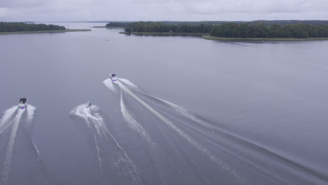 Cinematic Drone Shot of Jet Ski Following Three Motorboats on Lake Under Cloudy Sky
