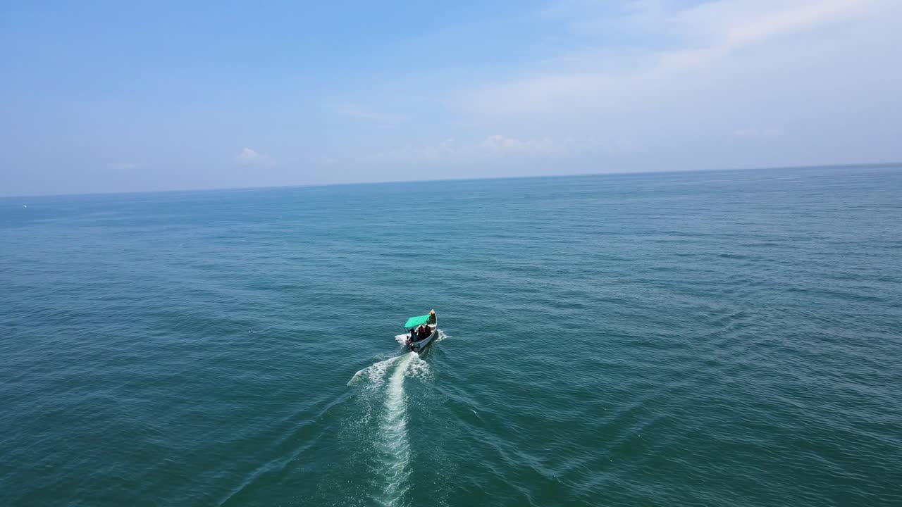 Aerial drone shot of a solitary fishing boat navigating the vast expanse of the ocean.