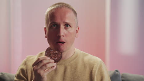 shocked man eats chocolate cookies with sign of bitcoin