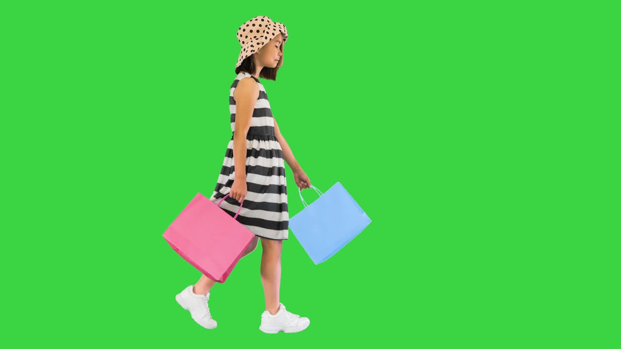 초록색 화면, 크로마 키에 쇼핑 가방과 함께 는 귀여운 작은 소녀