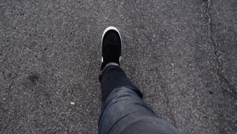 Young-person-in-jeans-and-skate-shoes-walking-through-concrete-parking-lot