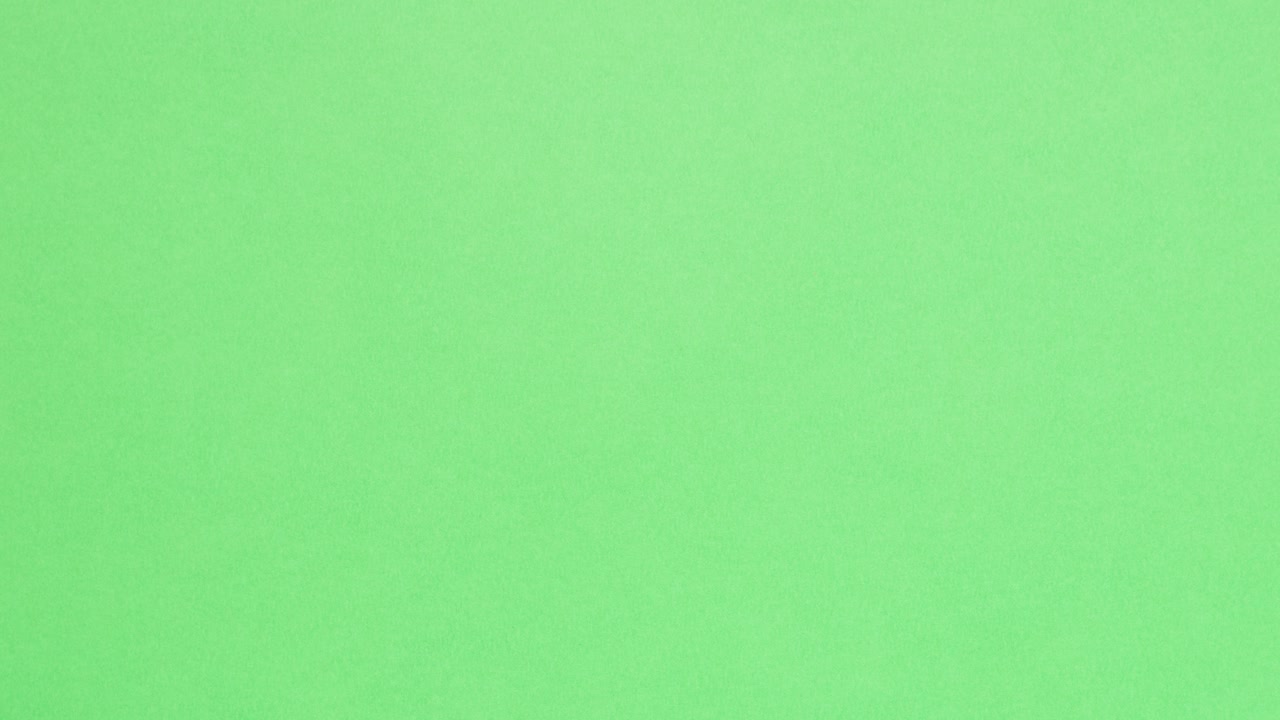 Orange crumpled paper unfolds on green in a stop motion transition