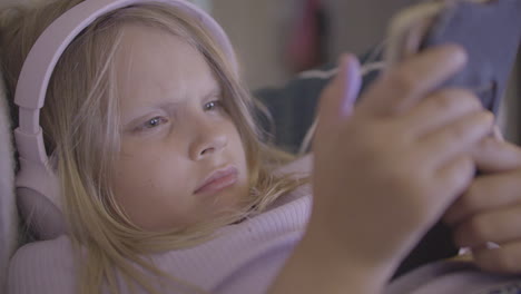 a young european girl wearing headphones and transfixed by her digital device