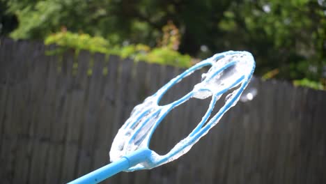 slow motion bubble wand creating multiple rainbow bubbles and popping outside