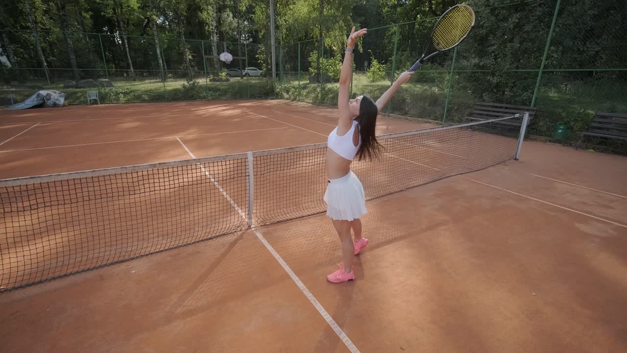 코치와 함께 야외 코트에서 테니스를 연습하는 젊은 여성. 코치는 선수가 그녀의 기술에 대해 일하면서, 운동 훈련 세션에서 그녀의 스트로크를 완성하는 동안 지침을 제공합니다.