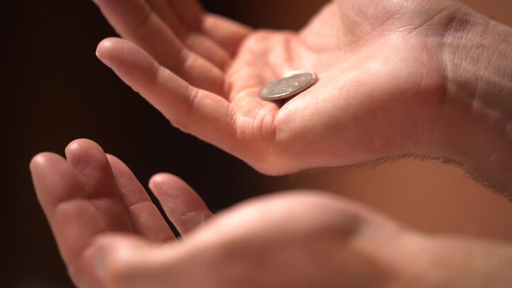 Monete al rallentatore che vengono passate da una mano all'altra in un primo piano.