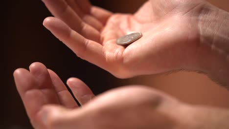 monedas en cámara lenta que se transfieren de una mano a la otra en un primer plano