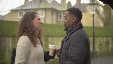 couple talking holding coffee