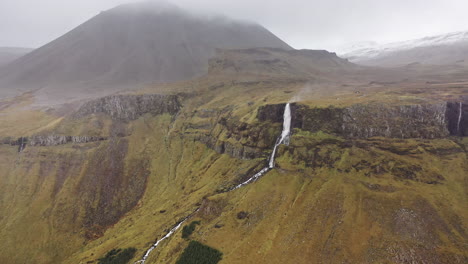 Drone-flight-towards-wind-blown-waterfall-in-Iceland