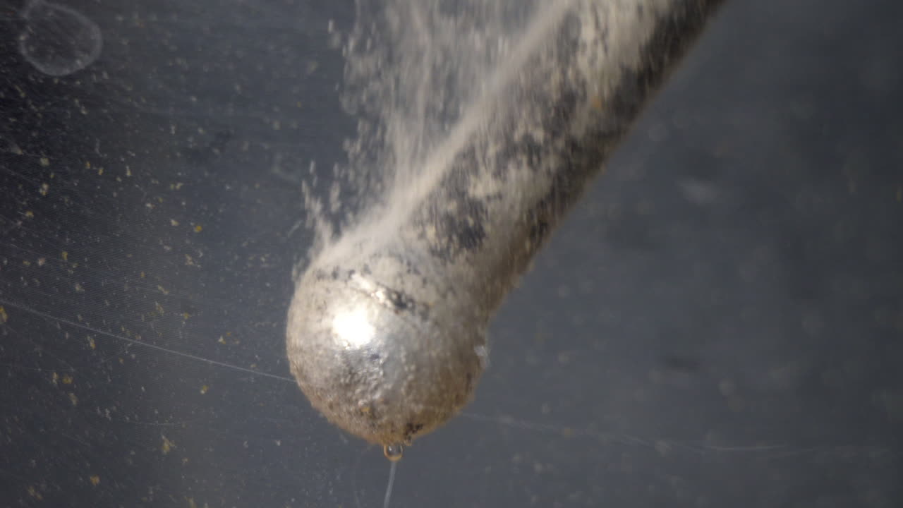 Hydrogen bubbles rise off of surface of c-clamp tommy bar during electrolytic cleaning