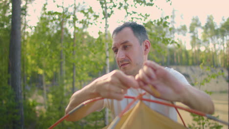 portrait of a man setting up a tent in the woods in slow motion