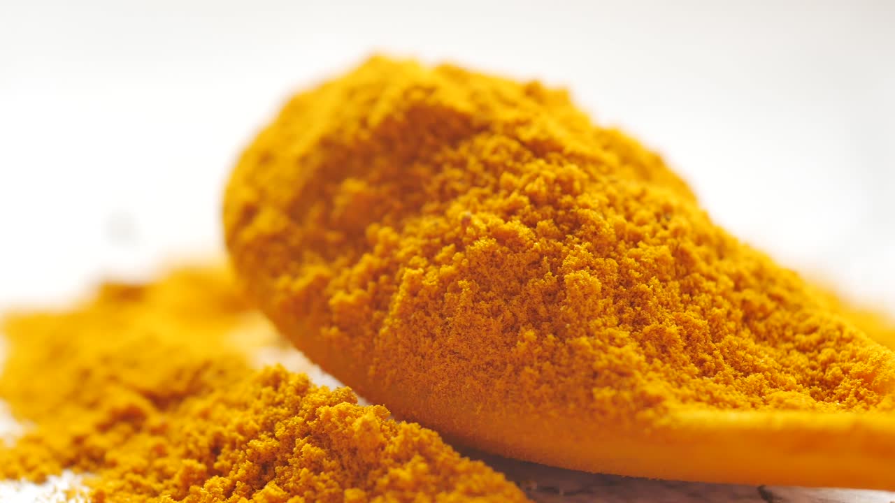 Detail shot of turmeric root powder on spoon