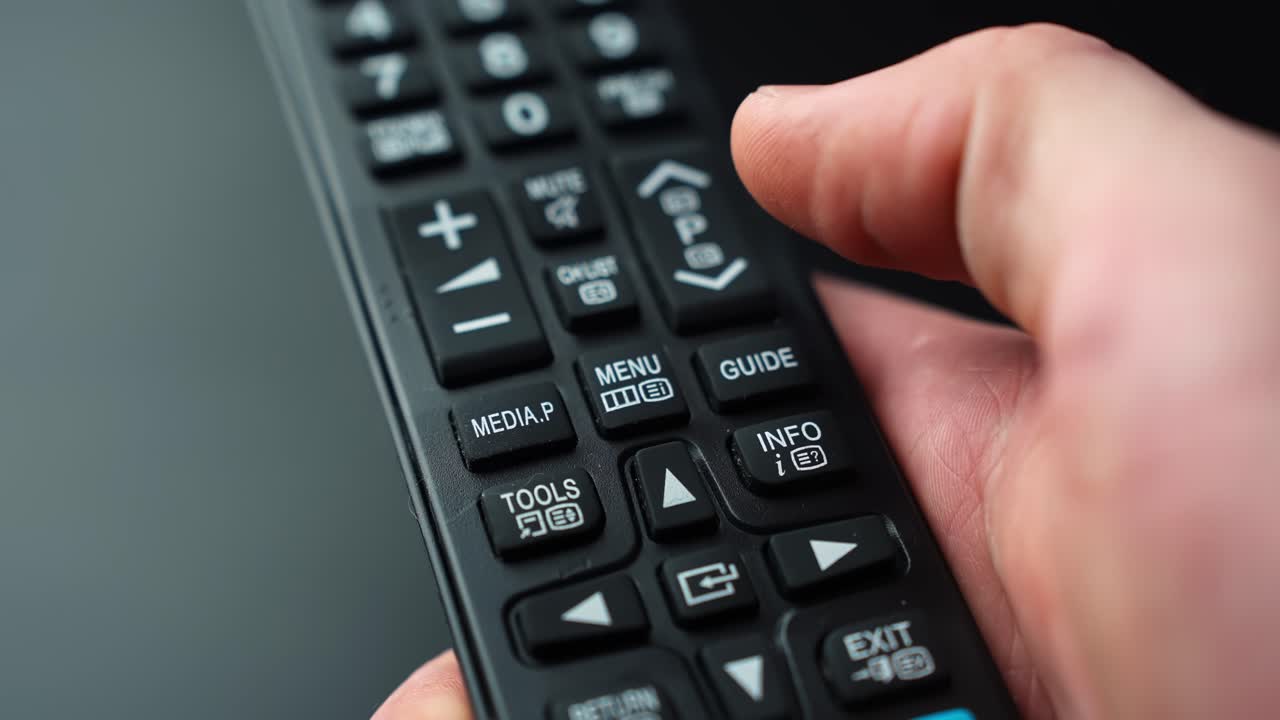 Close-up of a hand pressing the MENU button on a TV remote control, opening settings and on-screen options with shallow depth of field for home entertainment tech b-roll