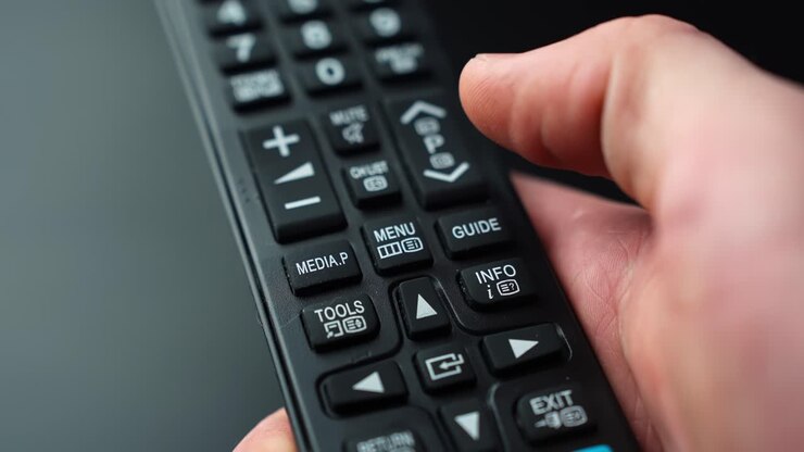 Close-up of a hand pressing the MENU button on a TV remote control, opening settings and on-screen options with shallow depth of field for home entertainment tech b-roll