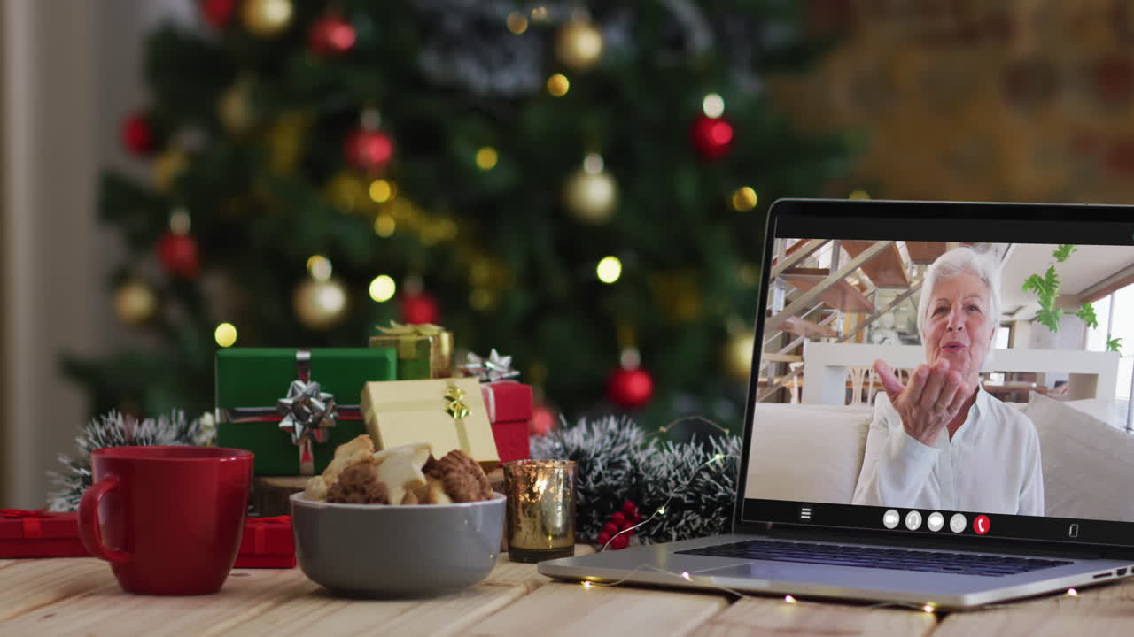 feliz mujer mayor caucásica en videollamada en computadora portátil, con decoraciones de navidad y árbol
